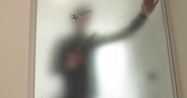Adamın biri cam kapıyı opak yapmak için klinikteki cam kapıya buzlu bir kaplama serpiştiriyor. Cama mat kaplama uyguluyorum..