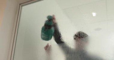 Adamın biri cam kapıyı opak yapmak için klinikteki cam kapıya buzlu bir kaplama serpiştiriyor. Cama mat kaplama uyguluyorum..