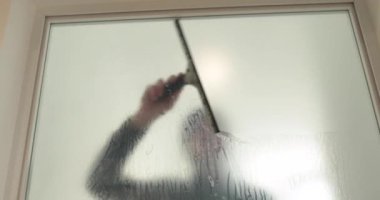 Adamın biri cam kapıyı opak yapmak için klinikteki cam kapıya buzlu bir kaplama serpiştiriyor. Cama mat kaplama uyguluyorum..