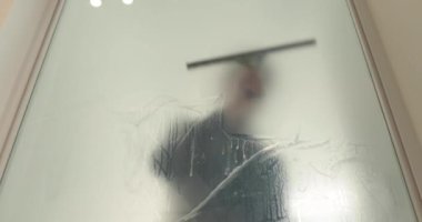 Adamın biri cam kapıyı opak yapmak için klinikteki cam kapıya buzlu bir kaplama serpiştiriyor. Cama mat kaplama uyguluyorum..