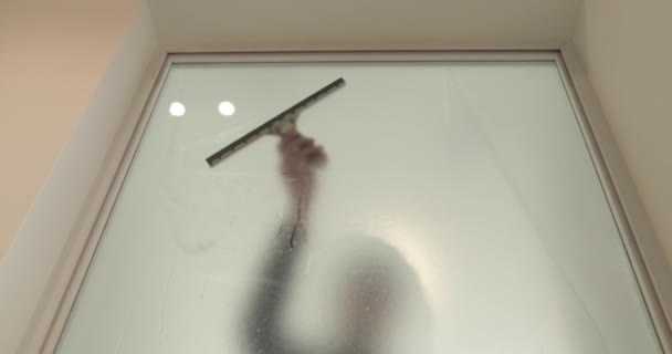 Ein Mann Klebt Eine Mattierte Beschichtung Auf Eine Glastür Einer — Stockvideo