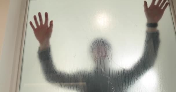 ある男は ガラスのドアを不透明にするために クリニックのガラスドアに凍ったコーティングを貼ります ガラスにマットコーティングを施す — ストック動画
