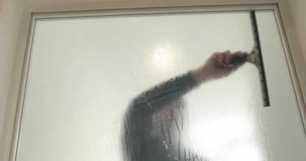 一名男子在诊所的玻璃门上贴上一层结霜的涂料 以使玻璃门不透明 在玻璃杯上涂上一层软垫 — 图库视频影像
