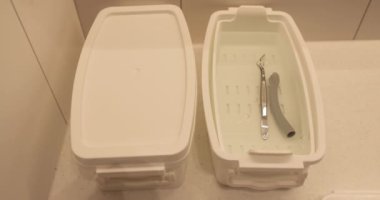Bir hemşire sterilizasyon ve dezenfeksiyon için bir kutuya tıbbi bir cihaz koyar..