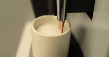 Kahve yapma süreci. Beyaz bardakta kahve yapan bir kahve makinesinin yakın çekimi. Kahve akışını profesyonel bir makineden bir fincana dolduruyorum..