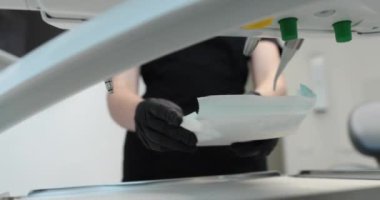 Maskeli bir hemşire diş ameliyatına başlamak için dezenfekte edilmiş aletlerle dolu bir tepsi taşır. Modern bir klinikte dişçilik ve diş tedavisi.