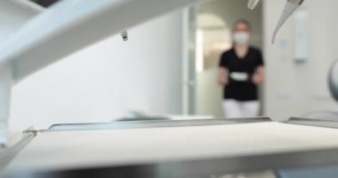 Maskeli bir hemşire diş ameliyatına başlamak için dezenfekte edilmiş aletlerle dolu bir tepsi taşır. Modern bir klinikte dişçilik ve diş tedavisi.
