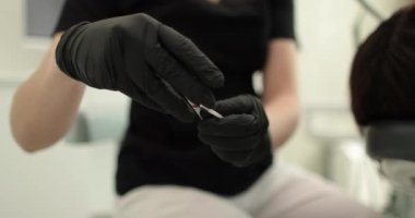 Diş aletleri ve diş macunu tutan dişçi ellerinin yakın çekimi. Steril maddeler kullanımı ve bir diş kliniğinde profesyonel diş temizliği süreci.