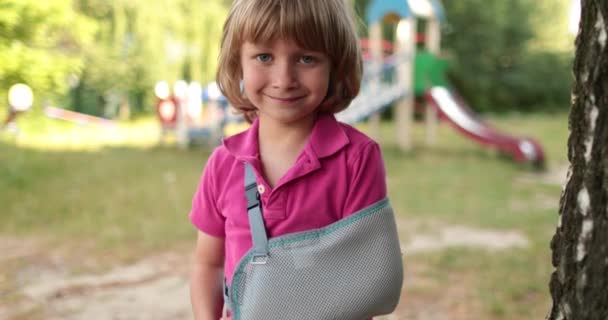 包帯に包まれた腕を持った小さなハンサムな少年 遊び場で負傷した子供 — ストック動画