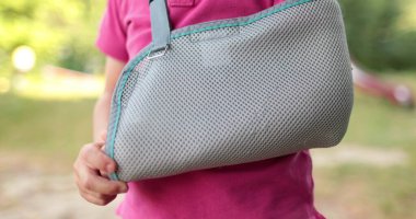 Bandajlı bir elin yakın çekimi. Açık bir alanda kolunda bandaj olan bir çocuk. Sınırlı insan hareketi. Çocuk yaraları.