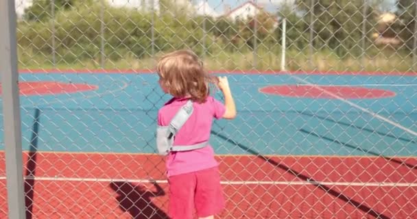 Ein Kind Mit Gebrochenem Arm Freien Der Nähe Eines Spielplatzzauns — Stockvideo