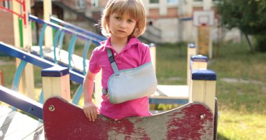 Bandajlı kolu kırık yakışıklı bir çocuk. Çocuk yaraları, kırık kol, bandajlı kol..