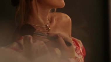 Gece elbisesi giymiş bir kadın aynanın önünde makyajını düzeltir. Karanlık bir odada aynanın önünde güzel bir kız. Video yansıtma.