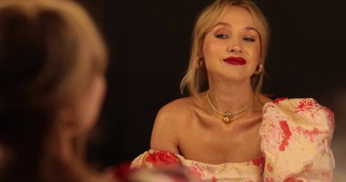 Akşam elbisesi giymiş, gülümseyen ve poz veren zarif bir kızın ayna portresi..