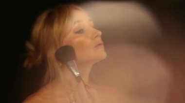 Gece elbisesi giymiş bir kadın aynanın önünde makyajını düzeltir. Aynanın karşısındaki kız. Karanlık bir odada aynanın önünde güzel bir kız. Çerçeveler yansıtılıyor.