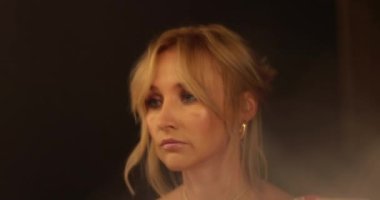 Güzel bir sarışının portresi aynanın önünde duruyor, kıyafetlerine bakıyor ve makyajını yapıyor. Aynanın önünde bir kadının yüzünü yakından çek..