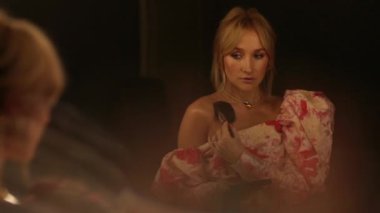 Güzel bir kadın soyunma odasındaki aynanın önünde makyajını tazeler..