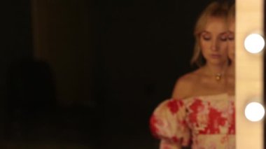 Güzel bir kadın soyunma odasındaki aynanın önünde makyajını tazeler..