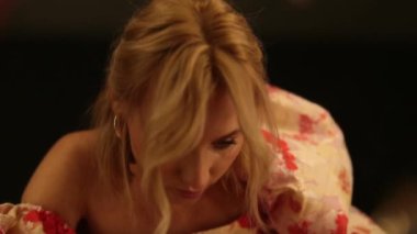 Karanlık bir soyunma odasında aynanın karşısında üzgün bir kadın..