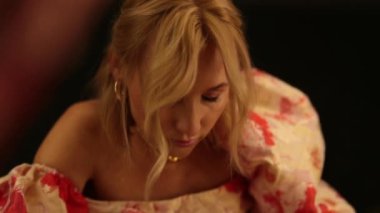 Karanlık bir soyunma odasında aynanın karşısında üzgün bir kadın..