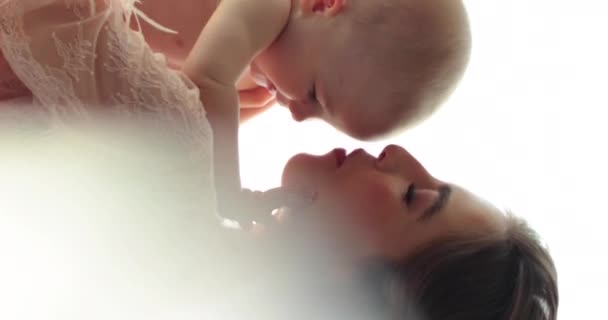 一个漂亮的母亲抱着一个赤身裸体的小孩的垂直镜头 一位有着漂亮发型和妆容的年轻母亲抱着一个婴儿 靠近点 慢动作 — 图库视频影像