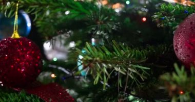 Parlak parlak çelenklerle süslenmiş Noel ağacı dalları ve Noel süslemeleri kameranın önünde yavaşça hareket ediyor