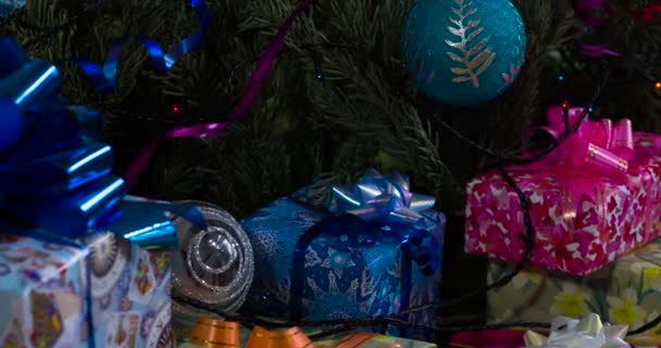 カメラは 輝く弓 クリスマスツリーの装飾や輝くガーランドで飾られたさまざまなギフトボックスに沿ってゆっくりと移動します — ストック動画