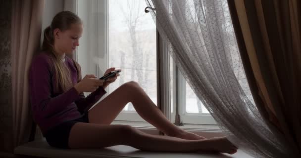 Girl Teenager Sitting Windowsill Holding Tablet She Looks Out Window — Stock Video