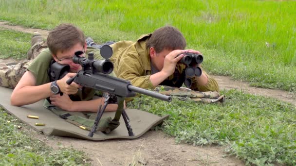 被狙击手拍到了 在一片草原的背景下 一对狙击手平躺在原处 枪手打了一枪 搭档用望远镜看了看 — 图库视频影像