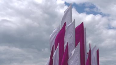 Bulutlu bir gökyüzüne karşı iki renkli festival bayraklarından oluşan piramit grubu