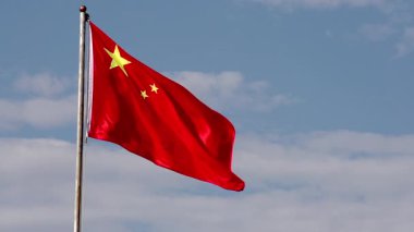 Çin bayrağı yavaşça dalgalanıyor. Çin 'in ulusal bayrağı hafif bulutlu mavi gökyüzüne doğru yavaşça dalgalanıyor.