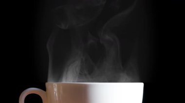 Bir fincan Aromatik Sabah Çayı. Bir fincan sıcak kahveden ince bir buhar damlası yükselir ve zarafetle döner. Arkaplan ışığı siyah arkaplanda fincanın bej rengini aydınlatır