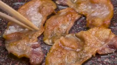 Çin usulü kızarmış pastırma. İnce pastırma şeritleri kızartma tavasında fokurdayan yağda kızartılır. Şef Çin çubuklarıyla domuz pastırması çeviriyor.