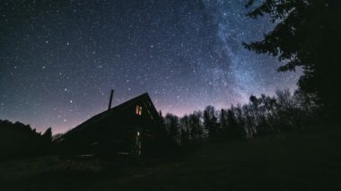 Peri masalı romantik gece gökyüzünde milyonlarca Samanyolu Galaksisi yıldızının vahşi orman doğasında ahşap kulübenin üzerinde dönmesiyle Astronomi Zamanı