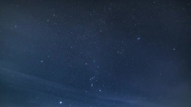 Mavi yıldızlı gece arkaplanının zamanı. Yıldızlar ve bulutlar derin kış gökyüzünde ay ışığında hareket ediyor. Astronomi Zaman aşımı 4K 
