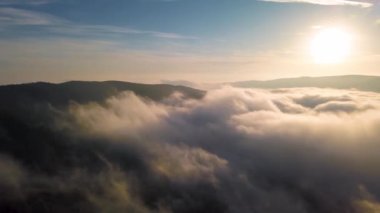Güneşli bir sonbahar sabahında güneşin doğuşunda sisli bulutların gökyüzü manzarası orman doğasının üzerinde hareket eder. 4K zaman aşımı görüntüleri 