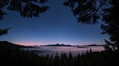 Romantik Yıldızlı Mavi Gece Gökyüzü 'nün zaman aşımına uğramış videosu. Yıldızlar, sisli vadideki orman dağları üzerinde hareket ediyor. Vahşi Astronomi manzarası. Zaman ayarlı 4k, yakınlaştır, Dolly vurdu, 