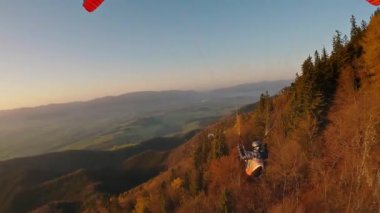 Peaceful proximity paragliding flight above autumn forest nature in alps mountains at beautiful sunset. Freedom Adrenaline sport adventure, Free like a bird, Relaxation flight, Follow Action camera