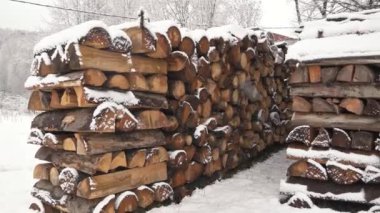 A pile of wood, Firewood stacked in a heap, prepared for the winter heating season in countryside. It is snowing outside in cold day. Steadicam video panorama