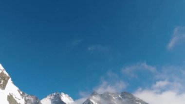 Donmuş sisli dağlar, güzel bir kış gününde, mavi gökyüzünden, karlı Alp Dağları 'nda, hafif kar yağan doğa manzarasını gözler önüne seriyor. Eğil Açık çekim. 