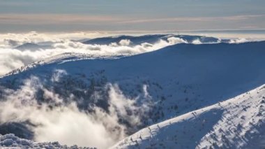 Time lapse video of Sunny winter in Carpathian mountains with misty clouds motion fast in valley in cold day in frozen nature. Timelapse, Slow zoom in, 4K. 