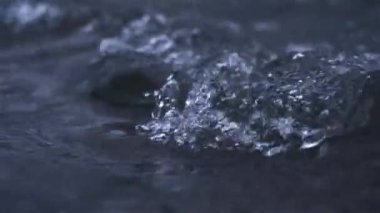 Clear Water flow in mountains stream river dark background slow motion