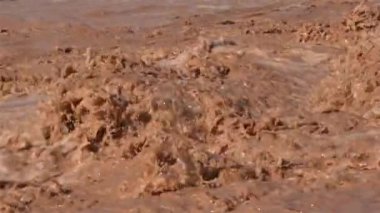 Slow motion of brown muddy water rapids splashing on flooded river after heavy stormy rain