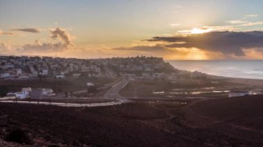 Colorful Sunset evening sky over Sidi Ifni town with road traffic in Morocco ocean coast Time lapse landscape, Zoom in 4k