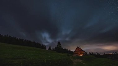 Bulutlar ve Samanyolu Galaksisi yıldızları vahşi doğada ahşap kulübe üzerinde hızlı hareket eder. Gece gündüz astronomi zaman aşımı 