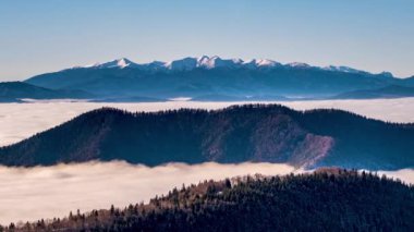 Alp dağlarının soğuk kış sabahı vadide hızla hareket eden sisli bulutların üzerindeki panoramik manzarası. Zaman aşımı, Pan. 