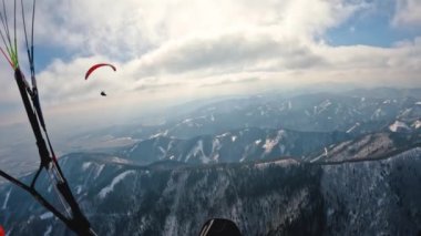 Kışın orman dağlarının üzerinde yamaç paraşütü yaparak uçan bir kuş gibi mavi gökyüzünde kümülüs bulutlarının altında termal uçuşlar. Adrenalin ekstrem spor özgürlük. Fpv aksiyon kamerası, yavaş çekim 4k video.