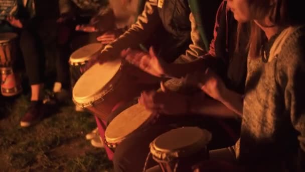 一群朋友坐在篝火边 在宁静的夏夜里打鼓 在杰姆贝身上打鼓的细节 — 图库视频影像