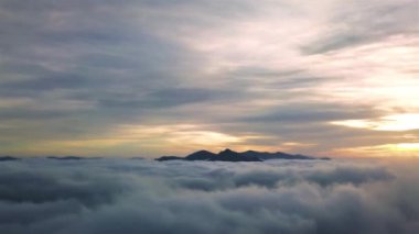 Güneşin doğuşunda sisli dağlarda gizemli gökyüzünün havadan görünüşü. Gri manzaralı arka plan gezintisi.