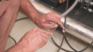 Elektrikçi kabloları tornavidayla bağlıyor. Erkekler üretim fabrikasında çalışıyor.